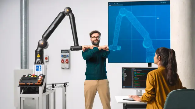 Bosch Rexroth APAS yardım robotuyla bir langırt masasında oyun oynayan iki çalışan.